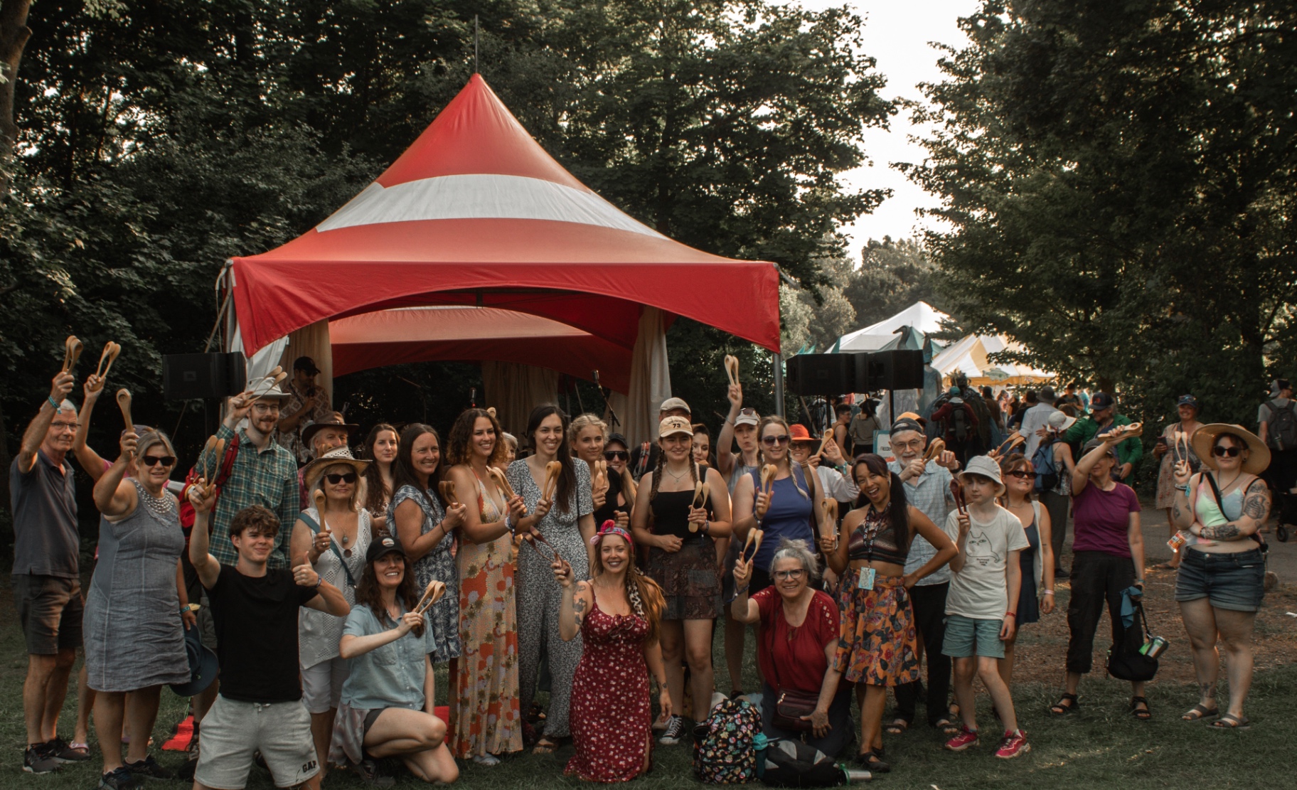 A large group of happy workshop participants holding Acadian musical spoons