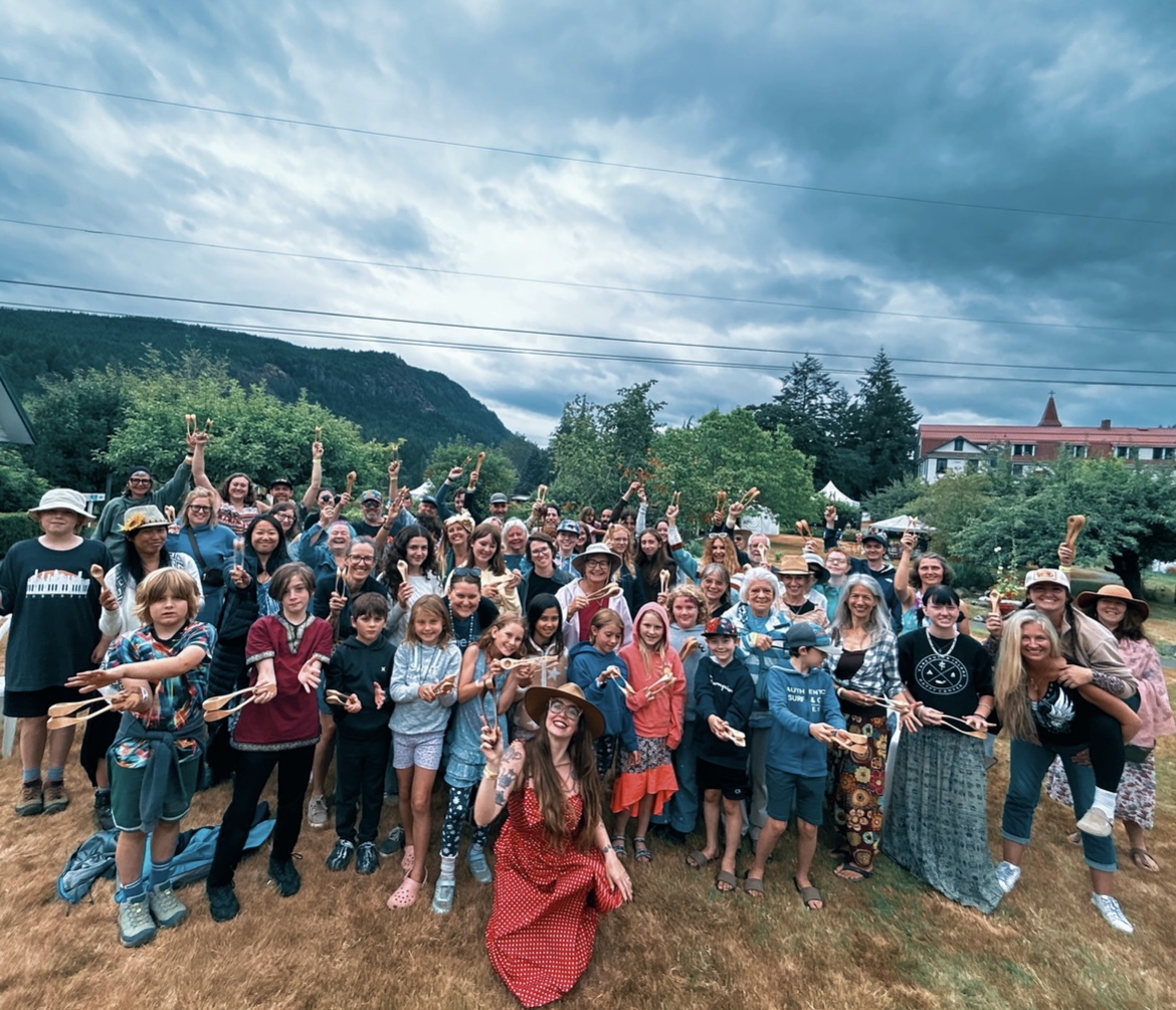 A large spoon workshop group holding their wooden spoons high in the mountains