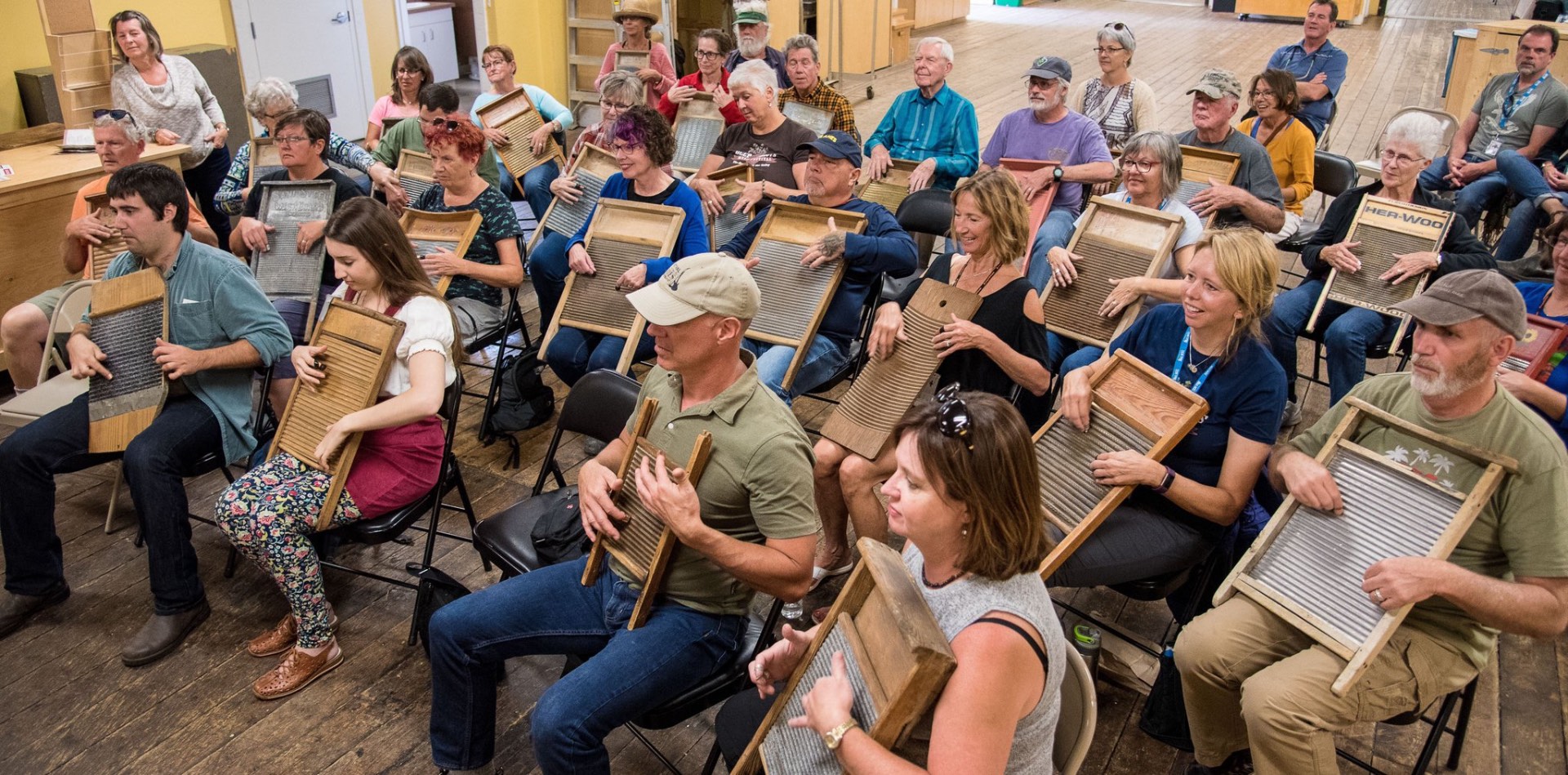A packed washboard workshop indoors with everyone strumming along