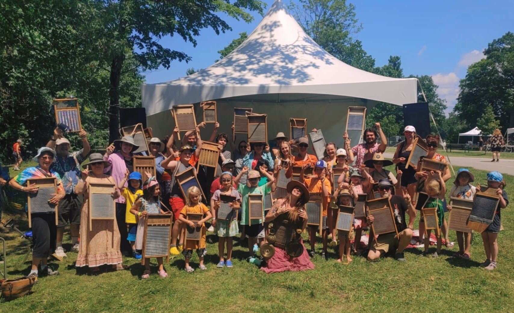 Workshop participants holding up washboards under the big white tent