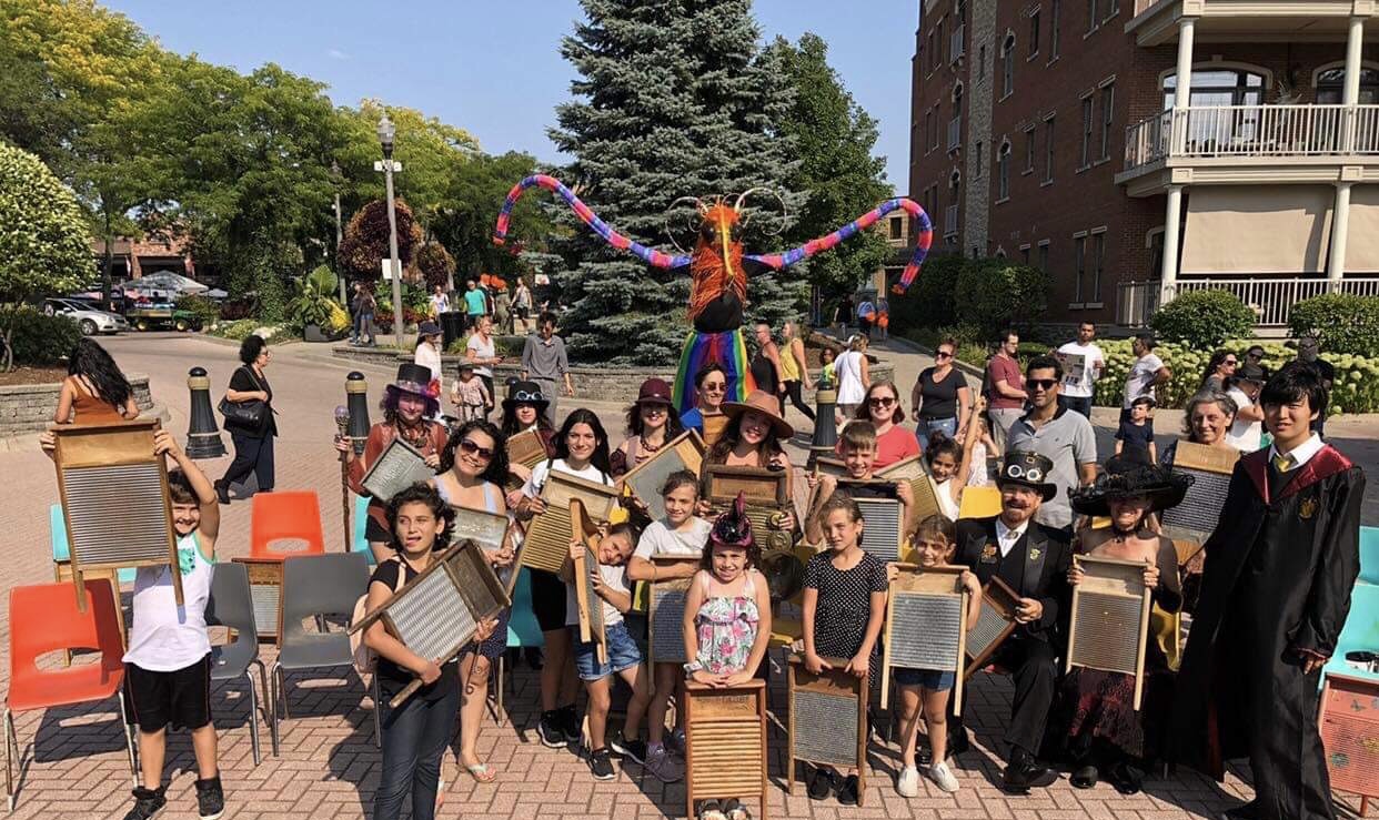 A street festival crowd of all ages holding up their washboards